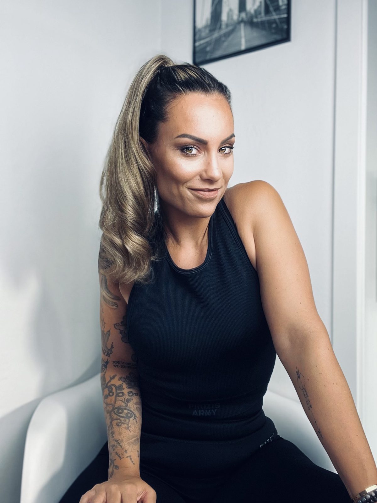 Stephy in schwarzem Sporttop auf einem weißen Sessel