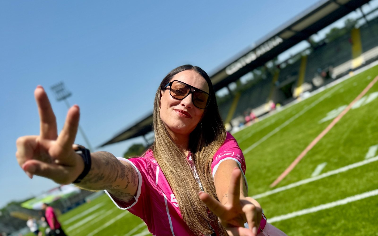 Stephy im pinken Trikot zeigt im Stadion das Peace-Zeichen